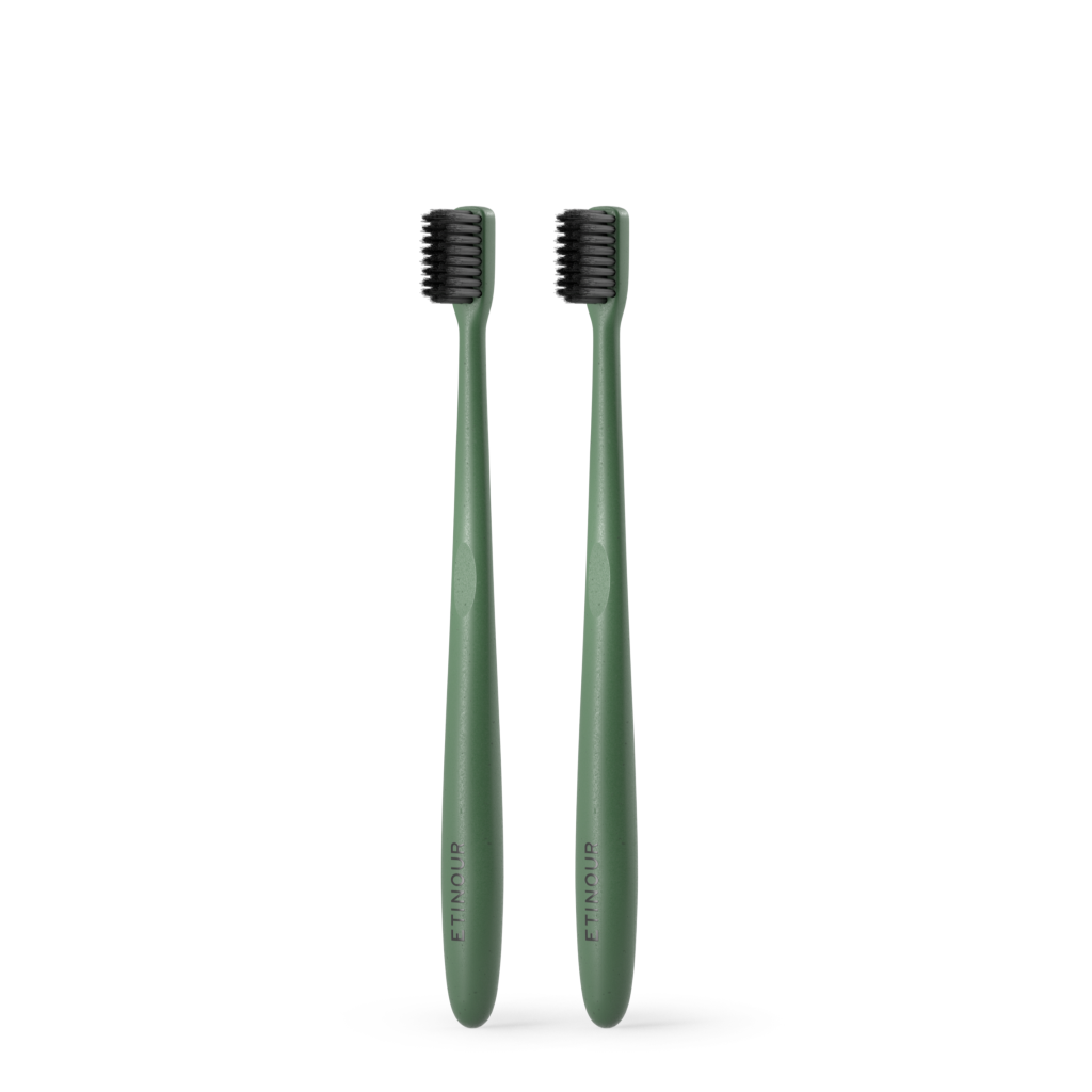 Two green Etinour Essential Toothbrush next to each other on white background