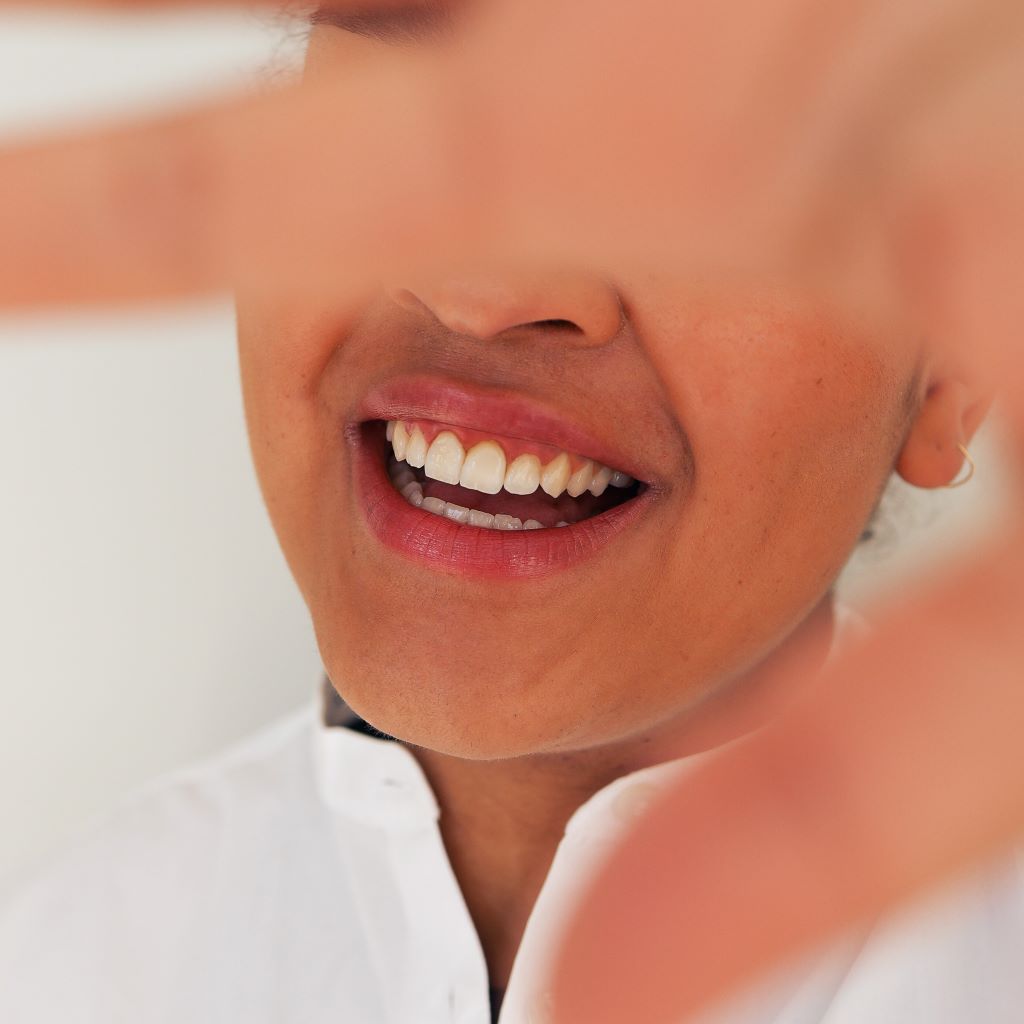 Young woman in white shirt smiling with straight and white teeth